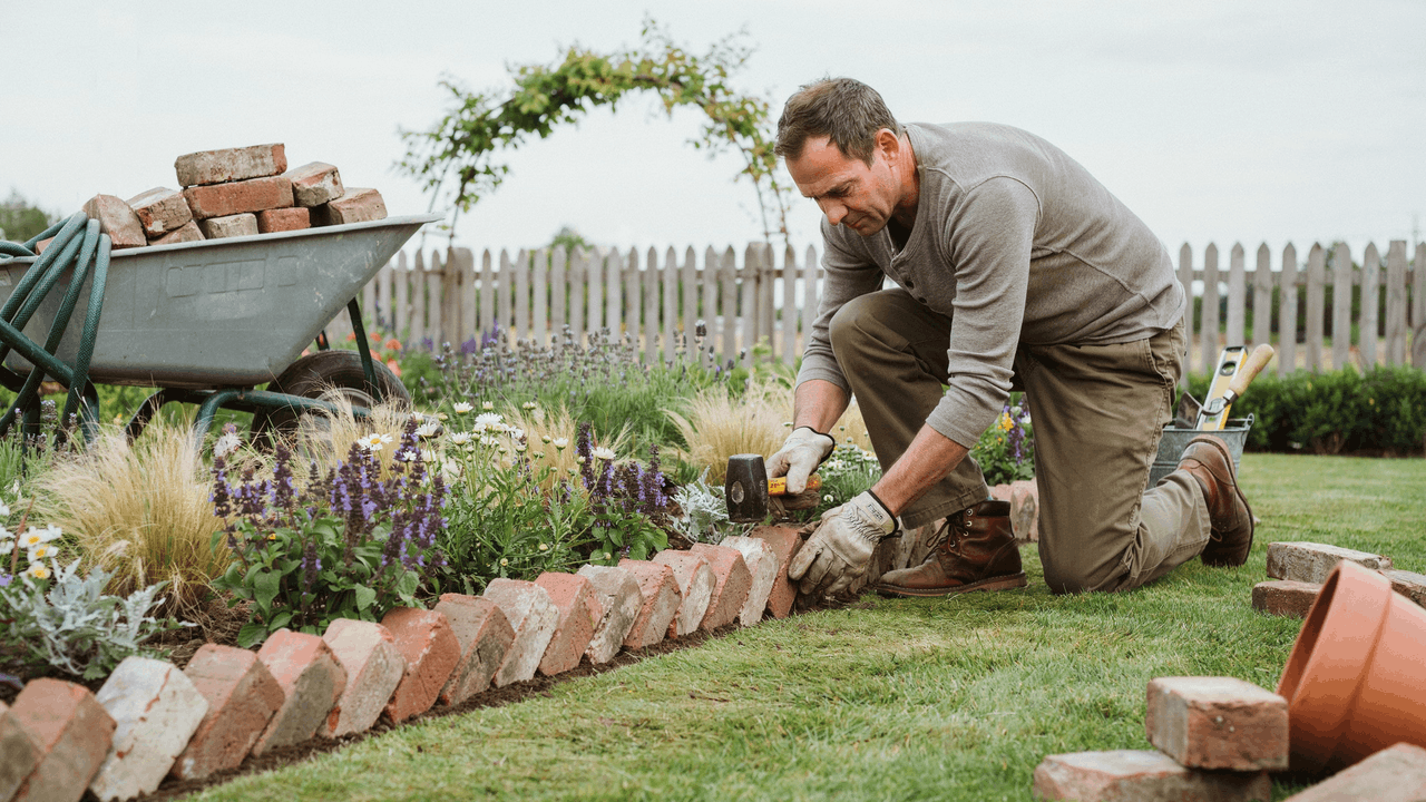 Garden border with reclaimed brick edging forming a structured boundary between lawn and flower beds.