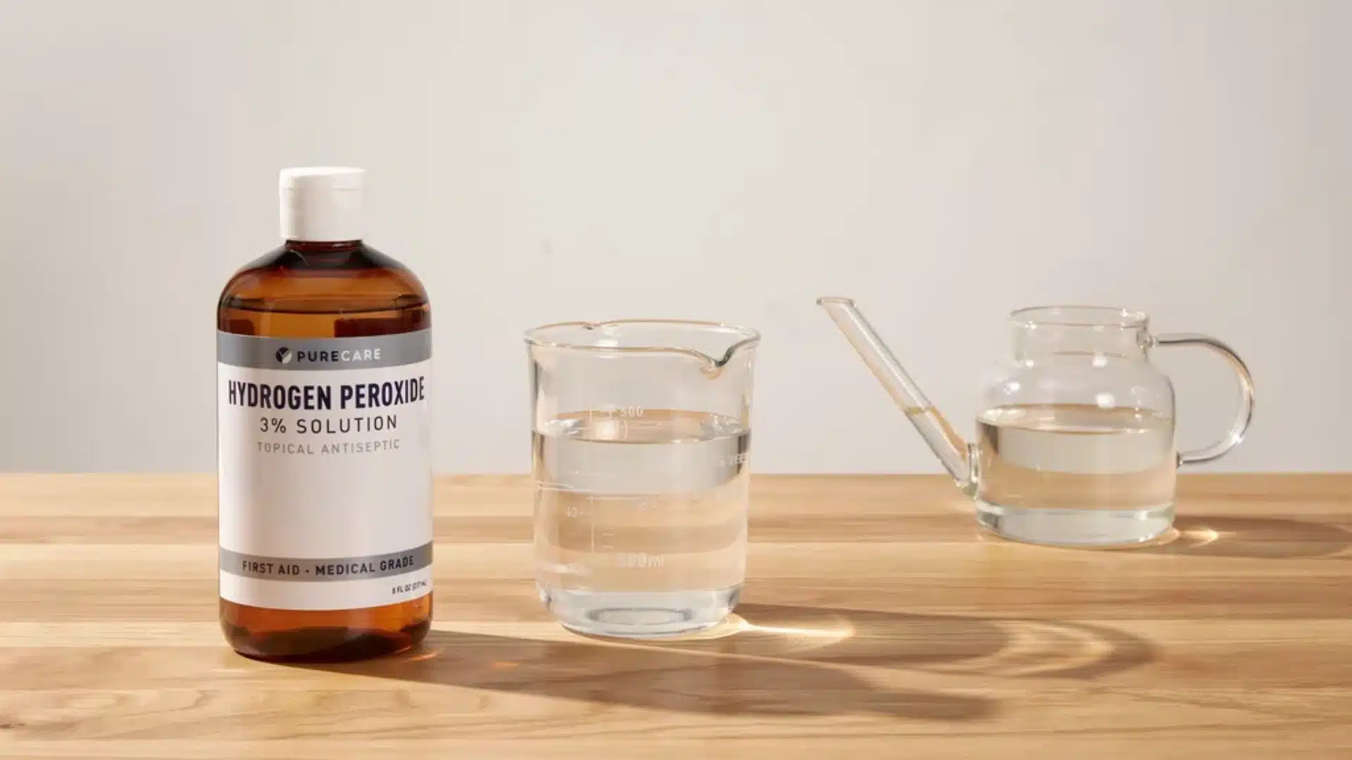 Hydrogen peroxide solution displayed with measuring glasses on a wooden tabletop for soil treatment.