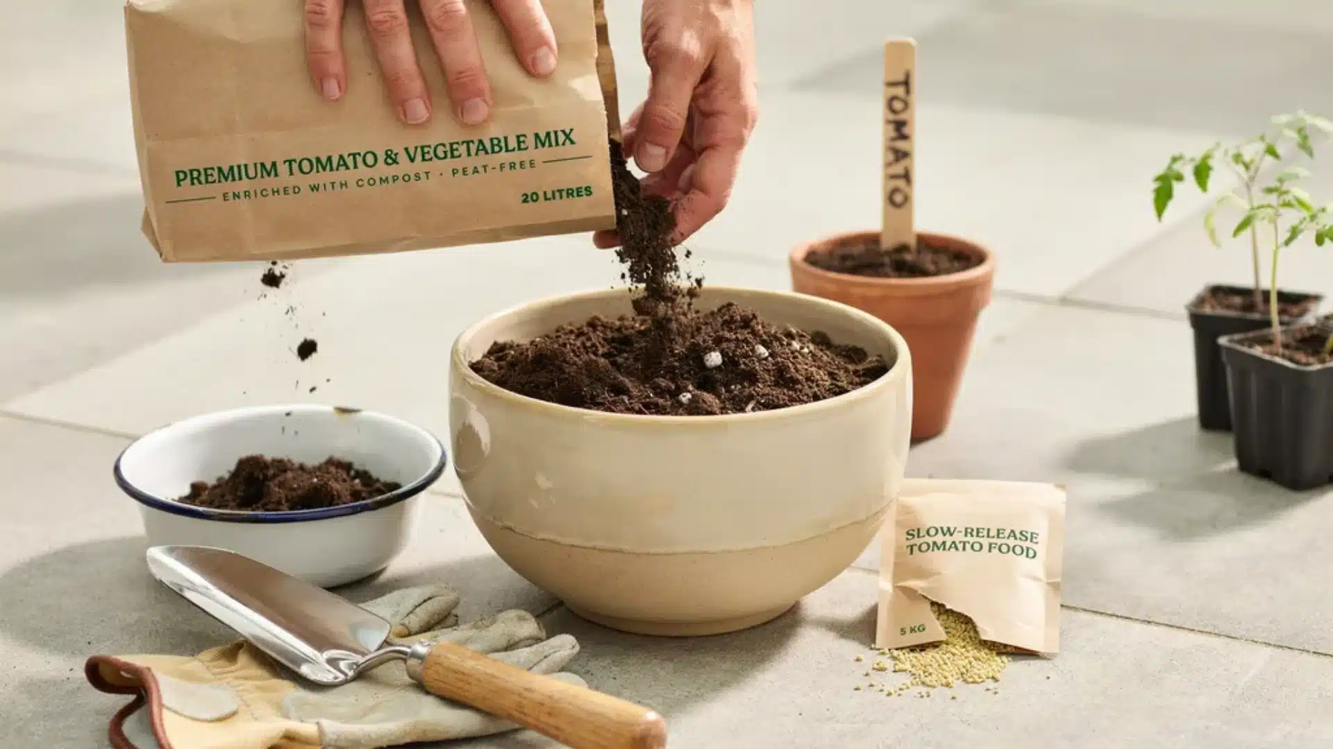 Close-up of rich potting soil being poured into a bowl, showing mix prepared for growing tomatoes in containers alongside gardening tools.